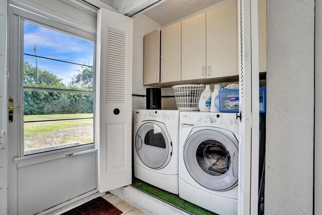 clothes washing area with cabinet space, separate washer and dryer, and a wealth of natural light
