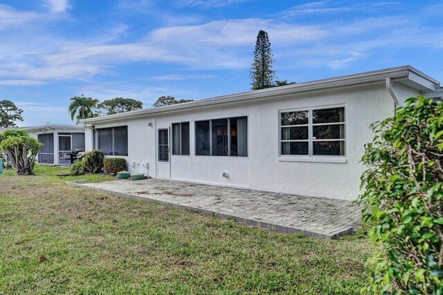 back of property featuring a patio, stucco siding, and a yard
