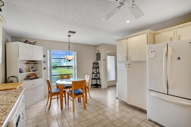 kitchen with ceiling fan, light countertops, freestanding refrigerator, visible vents, and pendant lighting