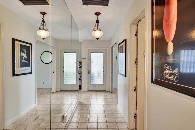 foyer with baseboards, visible vents, and light tile patterned floors