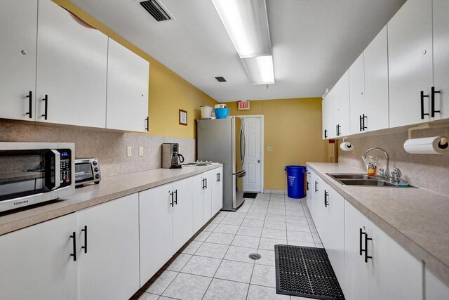 kitchen featuring a sink, appliances with stainless steel finishes, backsplash, and light countertops