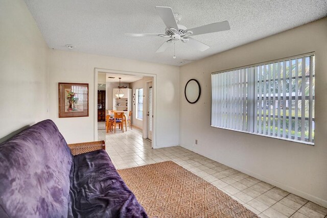 tiled living area with baseboards, a textured ceiling, and ceiling fan
