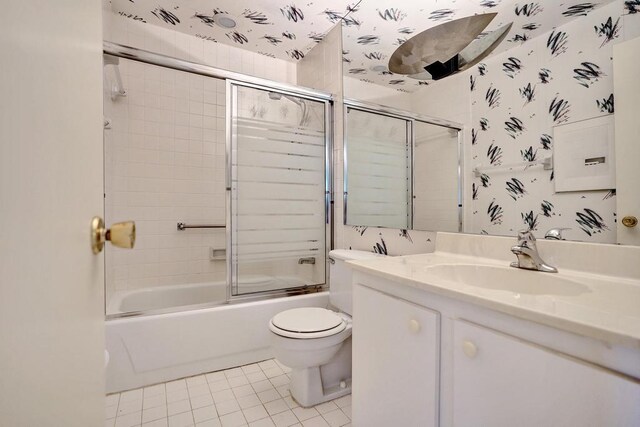 full bath with tile patterned flooring, shower / bath combination with glass door, toilet, and vanity