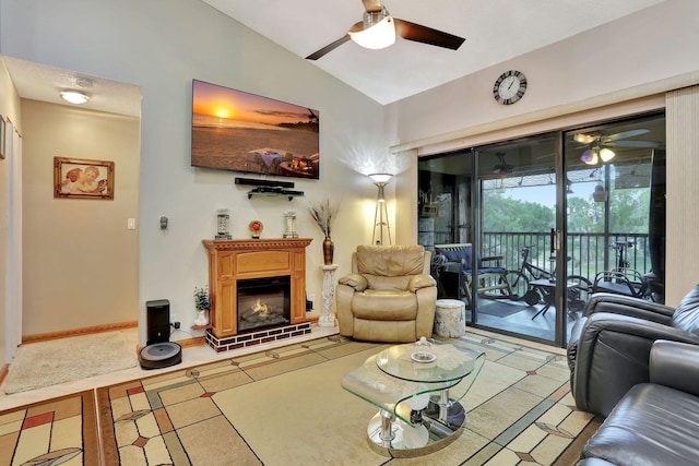 living room featuring lofted ceiling, ceiling fan, a lit fireplace, and baseboards