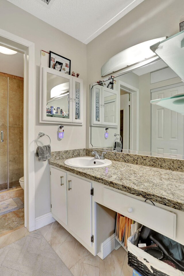 bathroom with a shower stall, vanity, toilet, marble finish floor, and baseboards