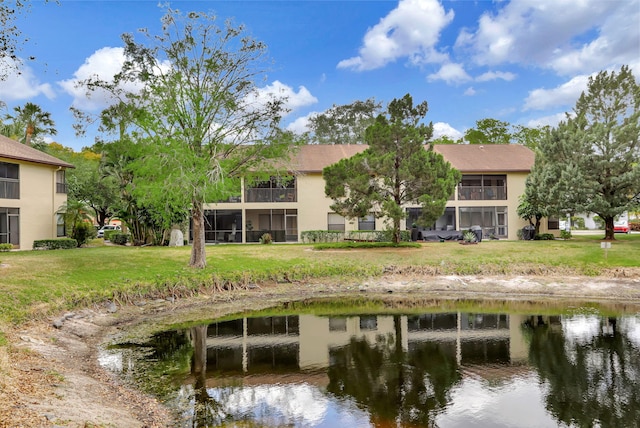 back of property with a yard, a water view, and stucco siding