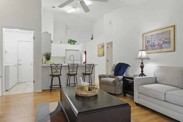 1054 NW Tuscany Dr, Port Saint Lucie, FL 34986 - living room featuring high vaulted ceiling, ceiling fan, washer / dryer, and light wood-type flooring