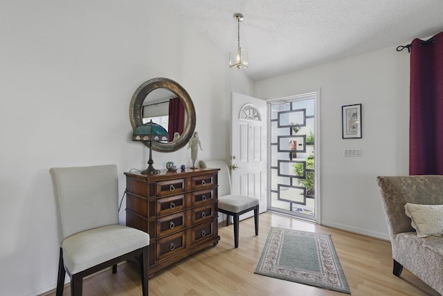1054 NW Tuscany Dr, Port Saint Lucie, FL 34986 - living area featuring an inviting chandelier, light wood-type flooring, baseboards, a textured ceiling, and lofted ceiling