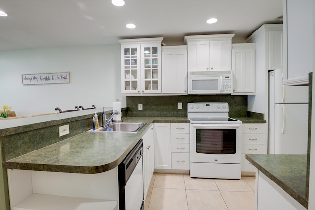 kitchen featuring dark countertops, a sink, light tile patterned flooring, and white appliances