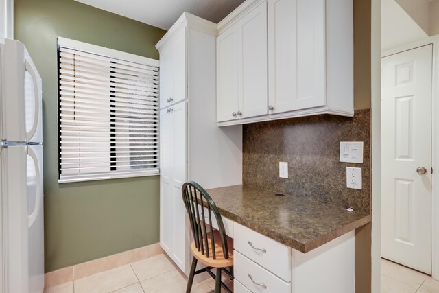 kitchen with white appliances, a kitchen breakfast bar, white cabinetry, a peninsula, and glass insert cabinets