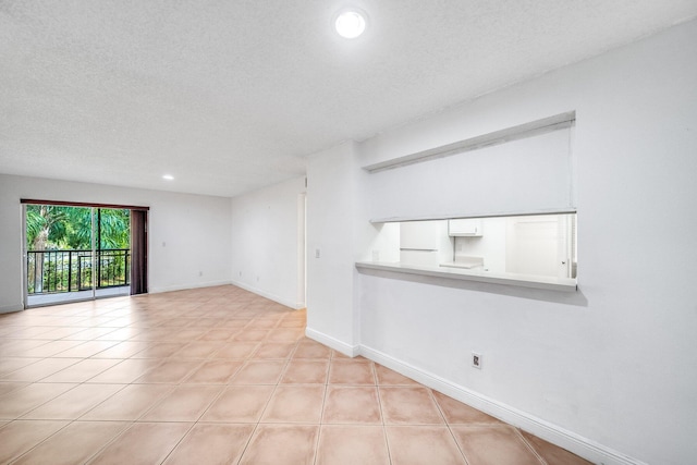 empty room featuring a textured ceiling, recessed lighting, and baseboards
