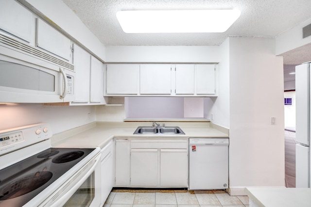 kitchen with white appliances, a textured ceiling, light countertops, and a sink