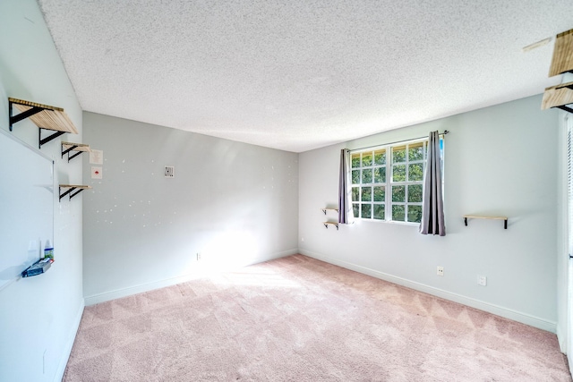 carpeted spare room featuring a textured ceiling and baseboards