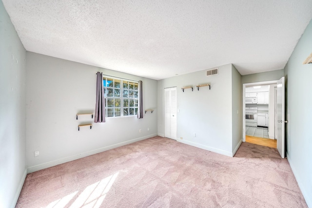 unfurnished bedroom with baseboards, visible vents, a textured ceiling, and carpet flooring