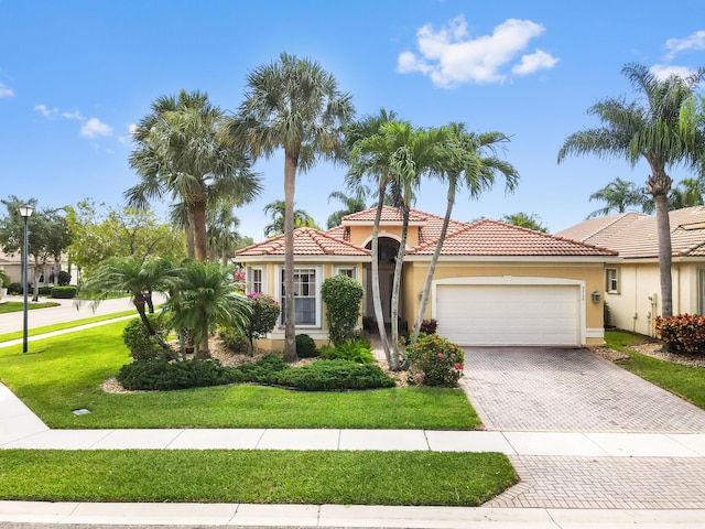 mediterranean / spanish-style house with an attached garage, driveway, a front yard, and stucco siding