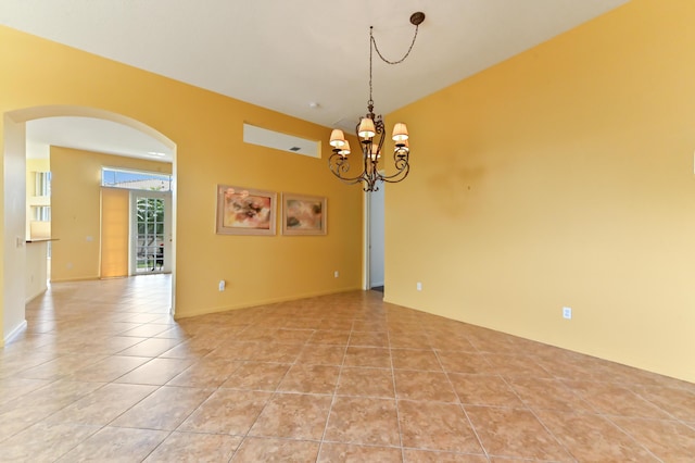 spare room with arched walkways, light tile patterned flooring, and a chandelier