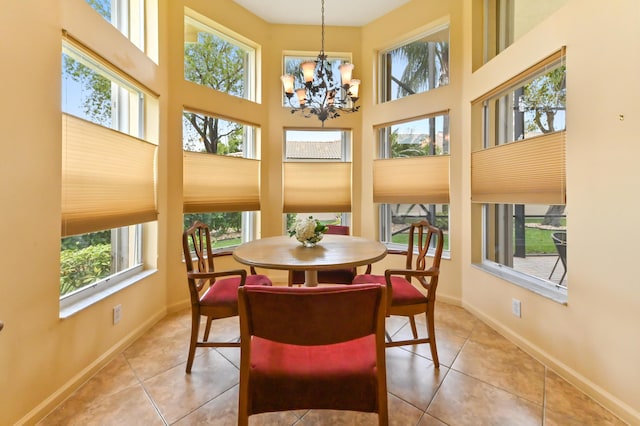dining space featuring a chandelier, light tile patterned floors, baseboards, and a towering ceiling