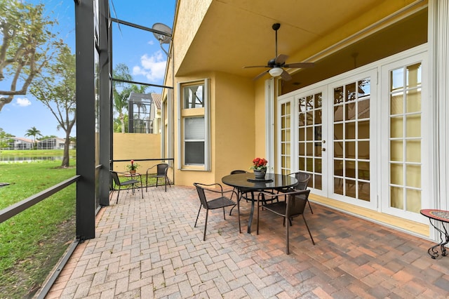 view of patio featuring french doors, a water view, a ceiling fan, and a lanai