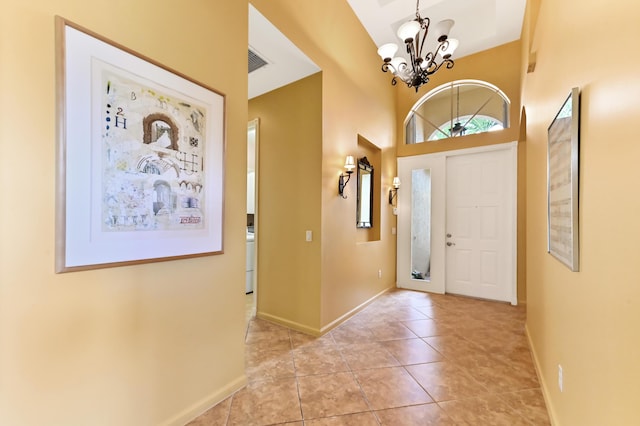 tiled foyer with a chandelier and baseboards