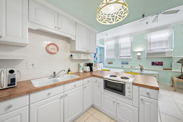 235 Sunrise Ave Unit 1051, Palm Beach, FL 33480 - kitchen featuring a sink, a peninsula, white cabinetry, light tile patterned floors, and backsplash