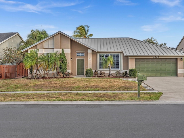 mid-century modern home with driveway, fence, a front lawn, an attached garage, and stucco siding