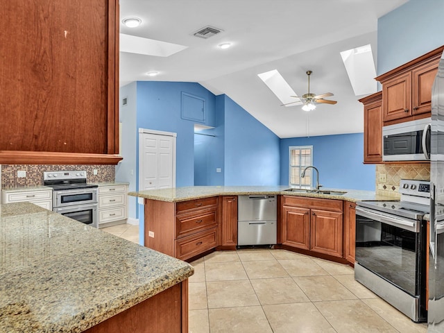kitchen with a sink, stainless steel appliances, light tile patterned floors, visible vents, and lofted ceiling with skylight