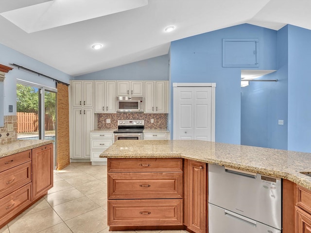 kitchen with lofted ceiling, light tile patterned floors, light stone counters, appliances with stainless steel finishes, and backsplash