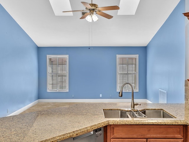 kitchen with brown cabinetry, a sink, a ceiling fan, and a skylight