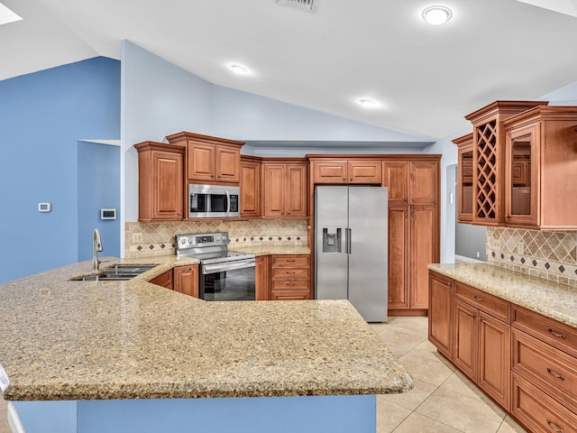 kitchen featuring a sink, vaulted ceiling, stainless steel appliances, and a peninsula
