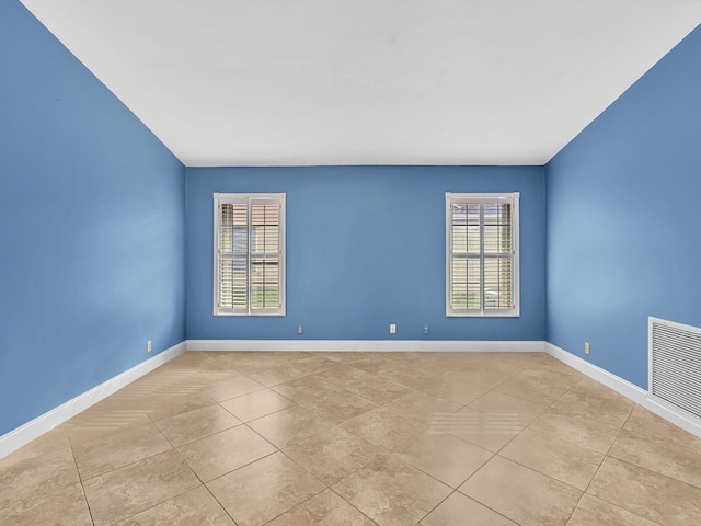 spare room featuring a healthy amount of sunlight, baseboards, light tile patterned flooring, and visible vents