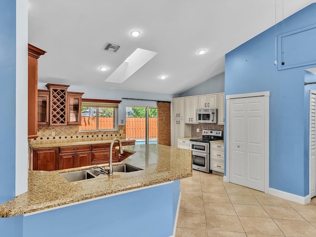 kitchen featuring decorative backsplash, visible vents, appliances with stainless steel finishes, a sink, and glass insert cabinets