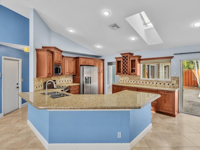 kitchen featuring a sink, vaulted ceiling with skylight, stainless steel appliances, a peninsula, and visible vents