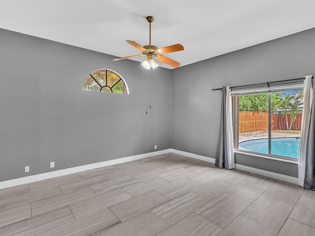 unfurnished room with baseboards, ceiling fan, and a wealth of natural light