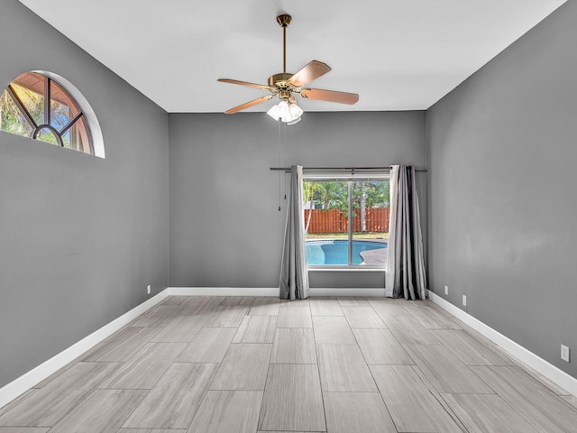 empty room with ceiling fan, wood finish floors, and baseboards