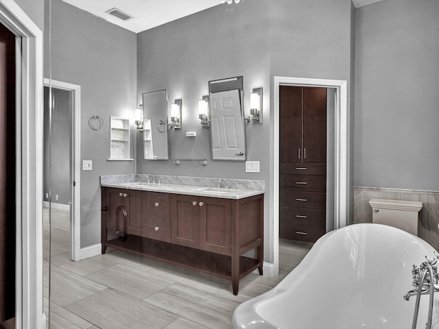 full bathroom featuring double vanity, visible vents, a sink, and a freestanding bath