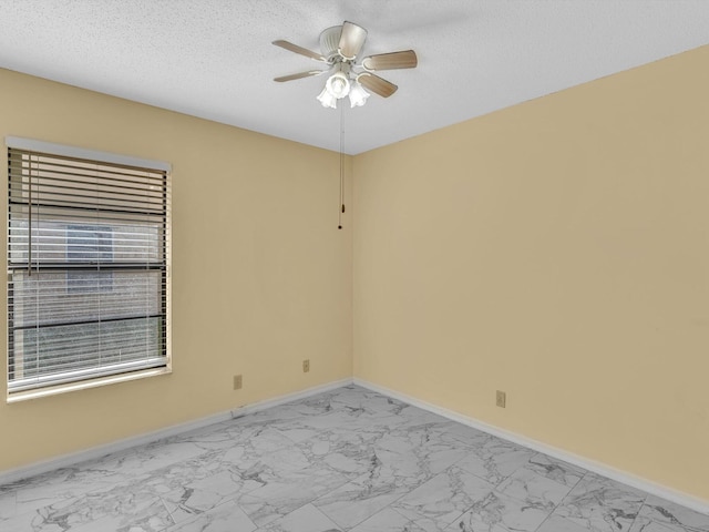empty room featuring baseboards, a ceiling fan, and marble finish floor