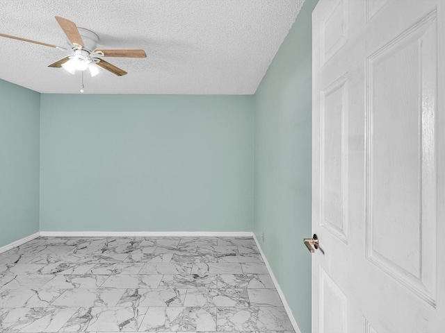 empty room with baseboards, a textured ceiling, marble finish floor, and ceiling fan