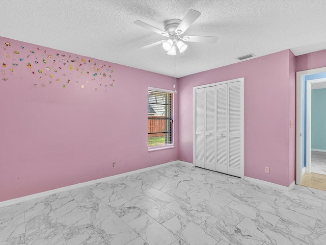 unfurnished bedroom featuring a textured ceiling, visible vents, baseboards, a closet, and marble finish floor