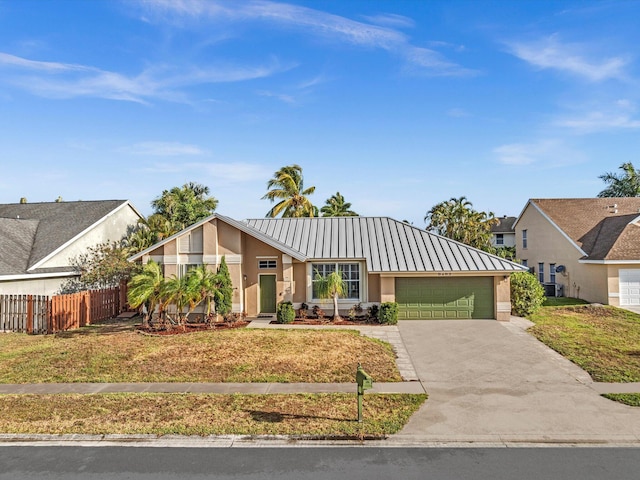 mid-century modern home featuring a garage, concrete driveway, fence, stucco siding, and metal roof