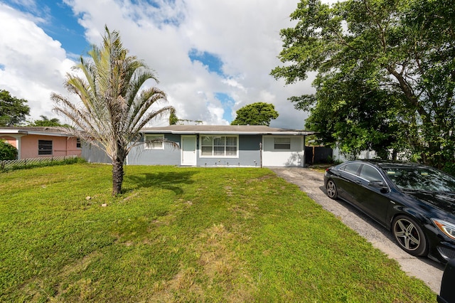 ranch-style home featuring stucco siding, fence, aphalt driveway, and a front lawn