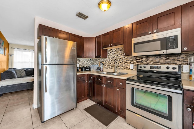 kitchen featuring backsplash, appliances with stainless steel finishes, light countertops, and a sink