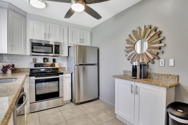 15108 Ashland Dr Unit 185, Delray Beach, FL 33484 - kitchen featuring light tile patterned floors, decorative backsplash, white cabinets, appliances with stainless steel finishes, and light stone countertops