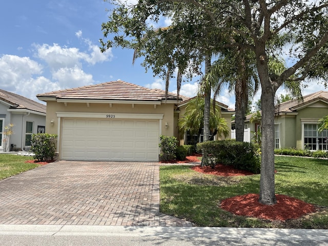 ranch-style home with stucco siding, decorative driveway, a garage, a tile roof, and a front yard