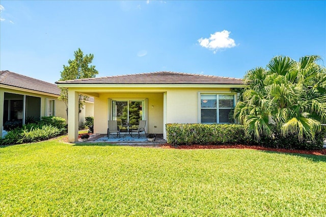 9925 SW Stonegate Dr, Port Saint Lucie, FL 34987 - back of house featuring stucco siding, a lawn, and a patio area