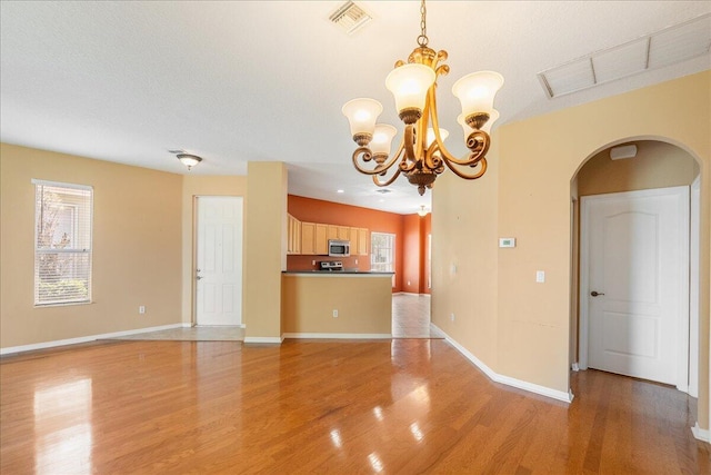 9925 SW Stonegate Dr, Port Saint Lucie, FL 34987 - unfurnished living room with arched walkways, light wood-style floors, plenty of natural light, and a chandelier