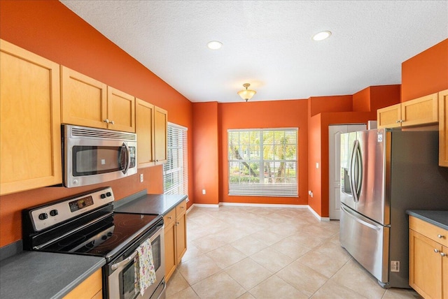 9925 SW Stonegate Dr, Port Saint Lucie, FL 34987 - kitchen with stainless steel appliances, dark countertops, baseboards, light tile patterned floors, and a textured ceiling