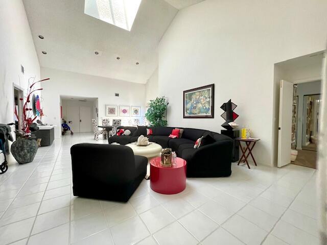 living room with light tile patterned floors, high vaulted ceiling, and a skylight