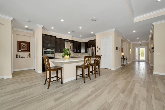 1055 Ember Ridge Run, Loxahatchee, FL 33470 - kitchen with a kitchen breakfast bar, light countertops, backsplash, recessed lighting, and light wood-style flooring
