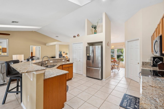 kitchen with a sink, visible vents, open floor plan, lofted ceiling with skylight, and appliances with stainless steel finishes