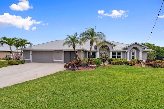 view of front of home with driveway, a garage, stucco siding, a front yard, and metal roof